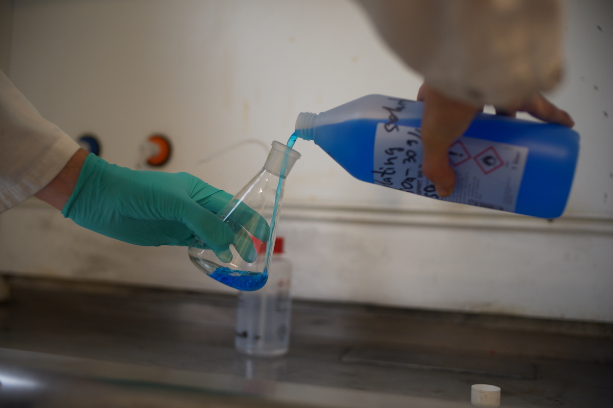 filling the bottle with blue chemical liquid